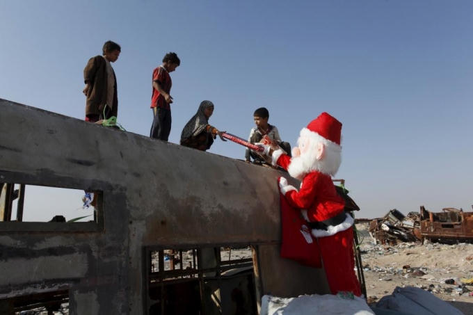 Những tình nguyện viên đóng giả thành ông già Noel đi tặng quà Giáng sinh cho trẻ em ở khu ngụ cư gần thủ đô Baghdad. (Ảnh: Reuters)