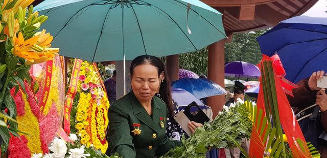 Bà Nguyễn Thị Thê, vợ liệt sĩ Vũ Trọng Hiên lặng lẽ đặt hoa cúc vàng lên từng nơi trong khuôn viên đài tưởng niệm.