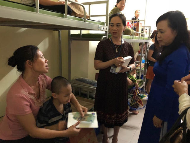 Bộ trưởng Y tế Nguyễn Thị Kim Tiến và bà Dương Thị Minh Thu (Trưởng phòng Công tác xã hội - BV Nhi Trung ương) thăm hỏi mẹ con chị Bùi Thị Lan.