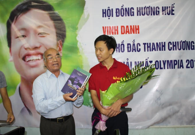 Nhà văn Trần Nguyên Vấn (bìa trái) tặng sách cho em Hồ Đắc Thanh Chương trong buổi vinh danh.