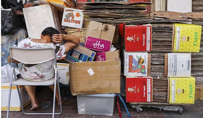 Một người cao tuổi ngủ gục bên các tấm bìa các tông ở To Kwa Wan