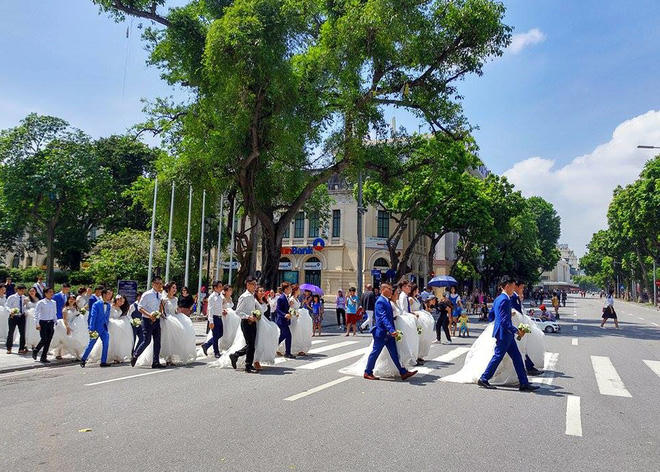 Cô dâu, chú rể tay trong tay dạo bước trên phố đi bộ quanh Hồ Gươm trong tiết trời nắng đẹp.