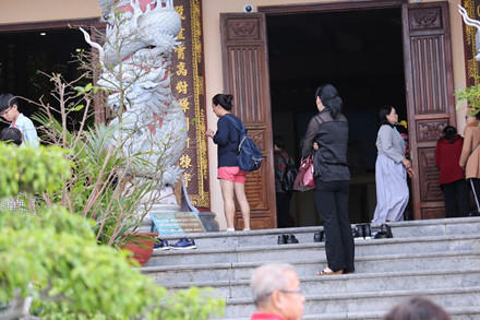 Một du khách ăn mặc "thiếu vải" được phật tử cho mượn váy trước khi vào chùa.