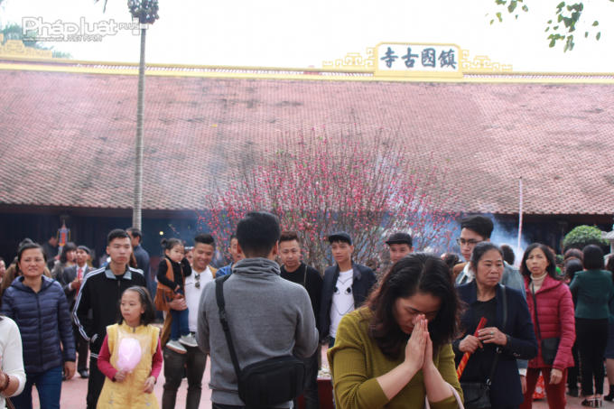 Nhiều người cầm theo hương, sớ... khi thắp hương, khấn vái khắp khu vực sân chùa.