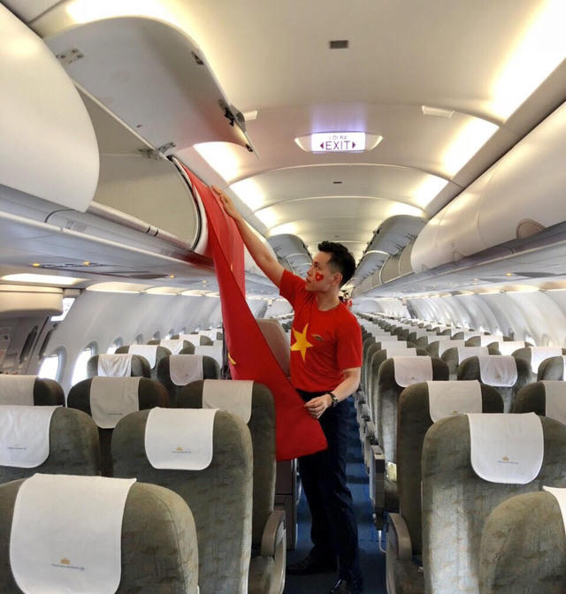 Tiếp viên Nguyễn Hữu Trung chỉnh trang lá cờ Tổ quốc trên máy bay chào đón các vận động viên Việt Nam.