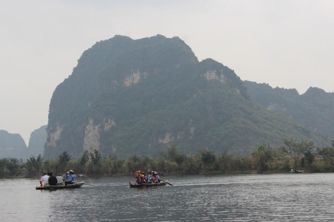 Từng đoàn du khách đi thuyền ngắm cảnh trên sông.