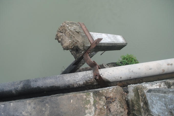 Một cột trụ lan can cầu đã gãy hoàn toàn, có thể rơi xuống sông bất cứ lúc nào. (Ảnh: Duy Ngợi).