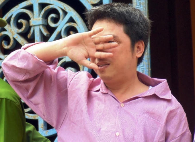 Huy che mặt khi bị dẫn giải sau phiên tòa.