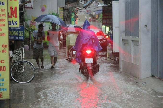 Phố Mỹ Đình (Nam Từ Liêm) một chiếc ô tô đỗ phía sau, đường nhỏ cộng với ngập làm cản trở đi lại của nhiều nguời.