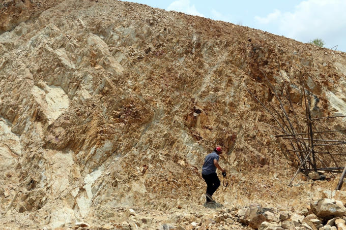 Một vách núi bị "xẻ đôi", trơ trọi đất đá.