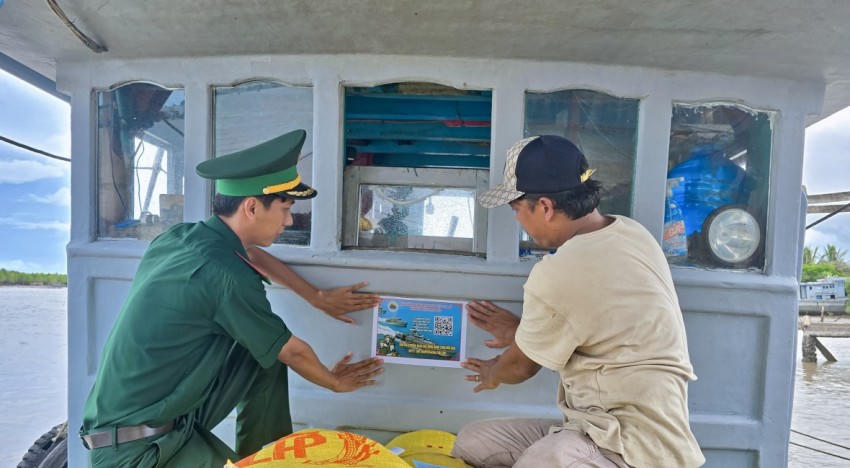 Cán bộ Biên phòng và ngư dân cùng dán mã QR IUU trên tàu cá để tiện tra cứu khi đi biển.