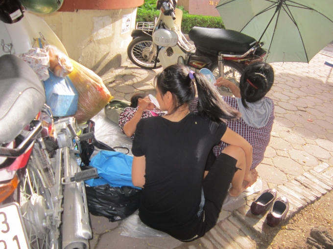 "Vạ vật" chờ con dưới cái nắng mùa hè, nhiều người ngả lưng ngay trên vỉa hè vì sốt ruột và lo lắng.
