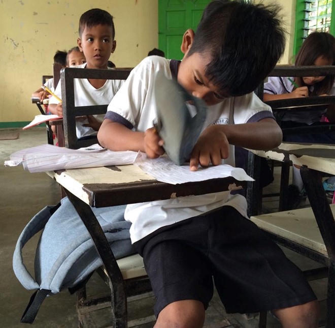 Harold dùng dép để tẩy vì không có đủ đồ dùng học tập. Ảnh: Rosalie Dela Cruz.