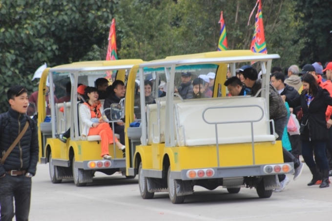 Du khách đi xe điện vào khu vực diễn ra lễ khai hội.