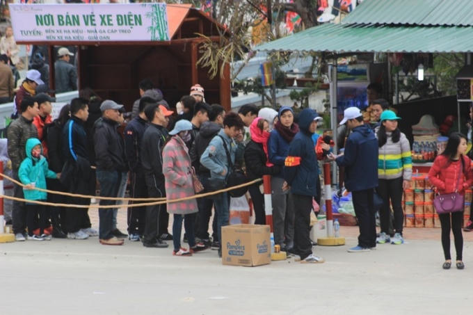 Du khách xếp hàng chờ lên xe điện.