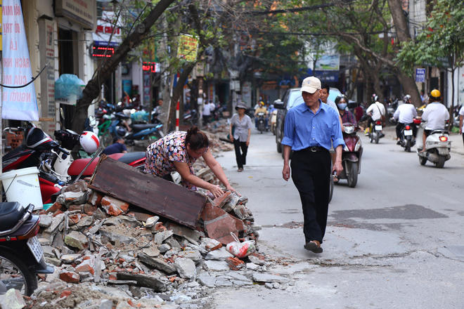 "Người đi bộ bị đẩy xuống lòng đường, còn gia đình tôi ở đây cũng khổ sở không kém, vật lộn với đống ngổn ngang này cả ngày", một hộ dân trên phố Vương Thừa Vũ nói.