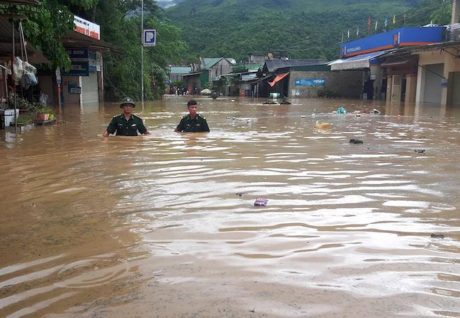 Lực lượng bộ đội biên phòng đi trong lũ giúp người dân. (Ảnh: Hải Thượng).