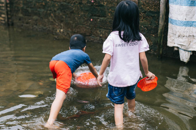 Trẻ em cầm cả rổ ra để bắt cá ngoài đường.