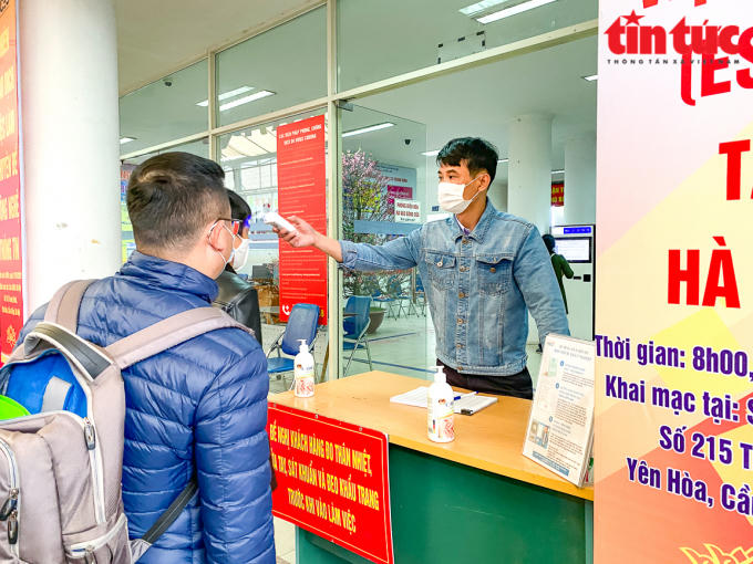 Người dân đến giao dịch tại Trung tâm dịch vụ việc làm Hà Nội (thuộc Sở Lao động-Thương binh và xã hội) được kiểm tra thân nhiệt và yêu cầu sử dụng nước rửa tay sát khuẩn.