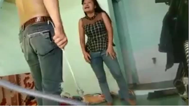 Hình ảnh người đàn ông cầm một vật nghi được làm bằng kim loại để hành hạ người phụ nữ.