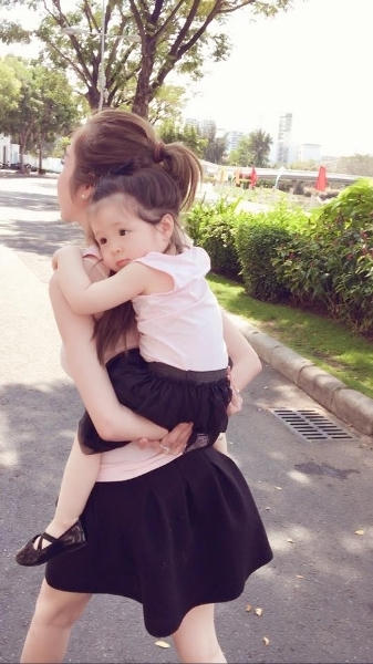 Bé Mộc Trà mắt tròn xoe, nằm ngoan ngoãn trên lưng mẹ Elly. Ảnh: facebook.