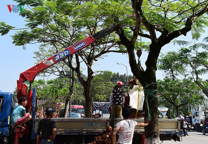 Khu vực chợ hoa xuân trước Phu Văn Lâu nhộn nhịp hối hả những giờ phút cuối cùng , 1 bức tượng gỗ được vẫn chuyển về nhà bằng xe cẩu.