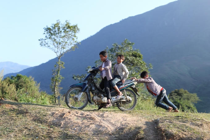 Một vài cậu bé đùa vui bên chiếc xe máy cũ kĩ.