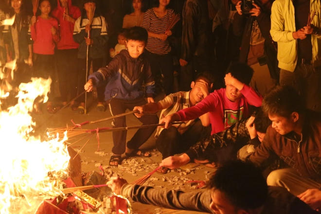 Những đứa trẻ buộc nén nhang vào cây sào dài để lấy lửa, ai cũng muốn được chia lửa đầu tiên.