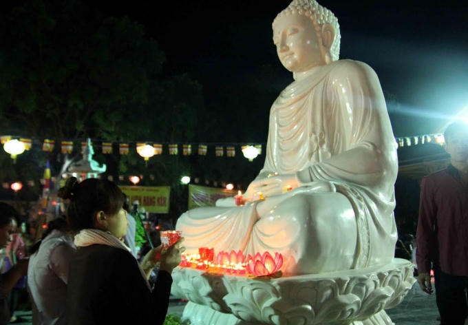 Mỗi người cầm một ngọn đèn được châm sáng từ ngọn đèn dưới chân Đức Phật.