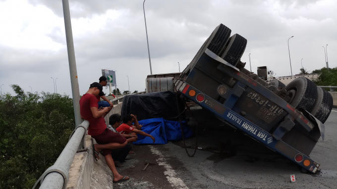 Hai cuộn sắt trên xe rơi xuống đường, bánh xe nằm cất lên trời.
