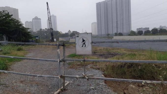 Máy móc thiết bị được phủ bạt kín mit. Nội dung ở biển cảnh báo thi công cũng bị lu mờ do công trình thi công kéo dài nhiều năm