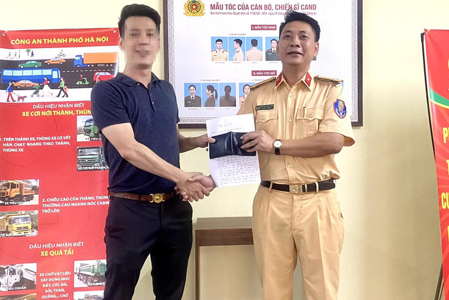 Trung tá Nguyễn Ngọc Tiến trao trả tài sản bị đánh rơi cho anh V. (Ảnh: Công an Hà Nội).