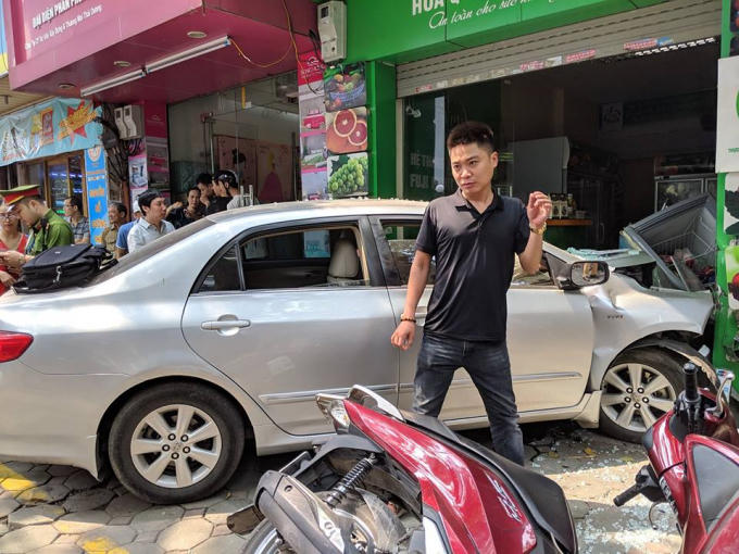 Hoa quả trong cửa hàng bị hư hỏng, nhiều xe máy nằm la liệt trên vỉa hè, chiếc Toyota bị hư hỏng nặng phần đầu, túi khí bung.