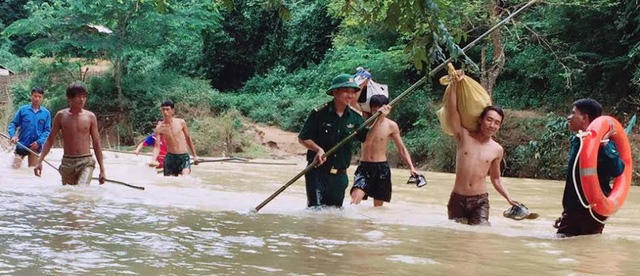 Các chiến sĩ biên phòng và thanh niên không ngại vượt nước lũ đưa trẻ và vận chuyển sách vở cho các em.