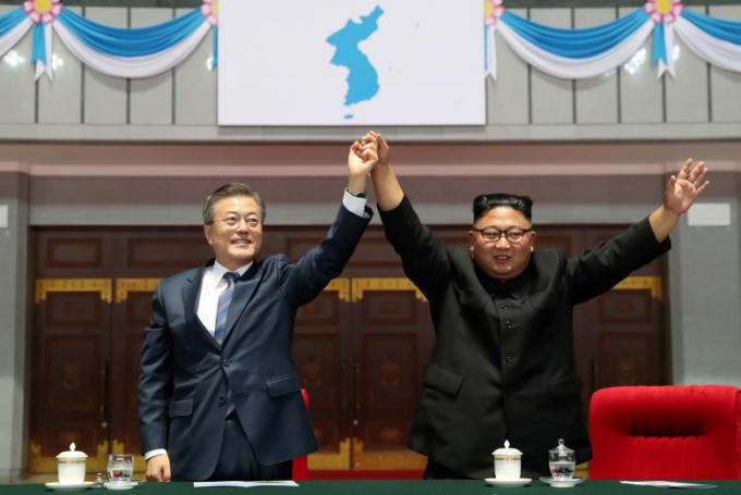 Tổng thống Hàn Quốc Moon Jae-in và Nhà lãnh đạo Triều Tiên Kim Jong-un nắm tay dưới lá cờ “Bán đảo Triều Tiên thống nhất” sau khi theo dõi màn biểu diễn tại sân vận động 1/5, ở thủ đô Bình Nhưỡng, Triều Tiên tối 19/9.