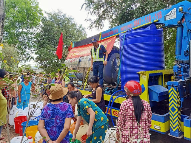 Xe vận chuyển nước của công ty TNHH cơ khí vận tải Thuận Thành Phong và bà con đang nhận nước ngọt sinh hoạt ở xã Bình Ân, Tăng Hòa và xã Bình Nghị, huyện Gò Công Đông