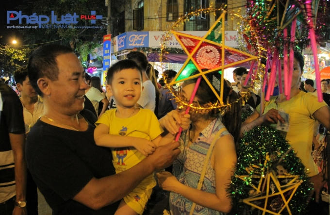 Một gia đình chọn mua cho con nhỏ chiếc đèn ông sao.