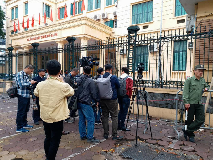 Trong lúc chờ làm thủ tục vào bên trong, phóng viên phải tác nghiệp qua hàng rào sắt.