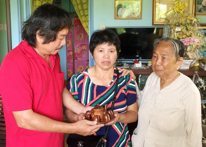 Nhà báo Nguyễn Phấn Đấu và mẹ tặng bà Mi (giữa) một bộ ấm trà làm bằng gáo dừa Bến Tre, với lời nhắn khi về Trung Quốc uống trà, sẽ nhớ về những người Việt Nam thân thiện, biết cảm thông cảm, chia sẻ . Ảnh: Hữu Danh.