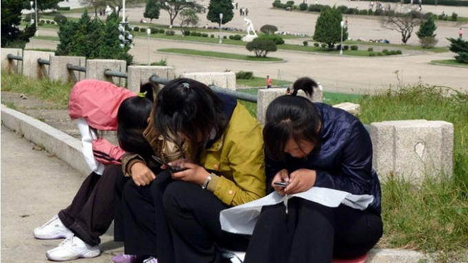 Các cô gái trẻ ở Triều Tiên sử dụng điện thoại di động tại công viên - Ảnh: AFP.