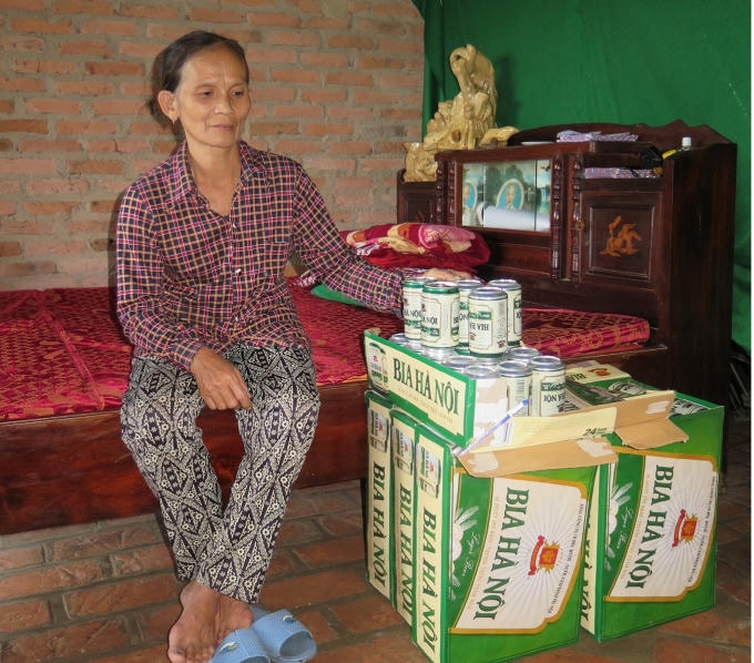 Bà Liễu bên những chai bia lỗi được gom lại. (Ảnh: Văn Hoàng)