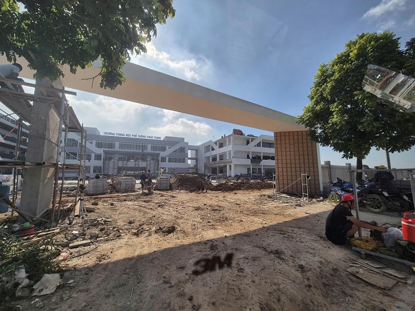 Công nhân xây dựng không có bảo hộ lao động vẫn đang trèo giáo để thực hiện việc trát tường hạng mục cổng chính của Trường THPT Phúc Thịnh.