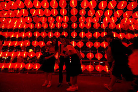 Chụp ảnh lưu niệm trên đường phố trang hoàng đầy đèn lồng đỏ ở Bangkok (Thái Lan) đêm 29 Tết, nhằm 26-1. Ảnh: REUTERS