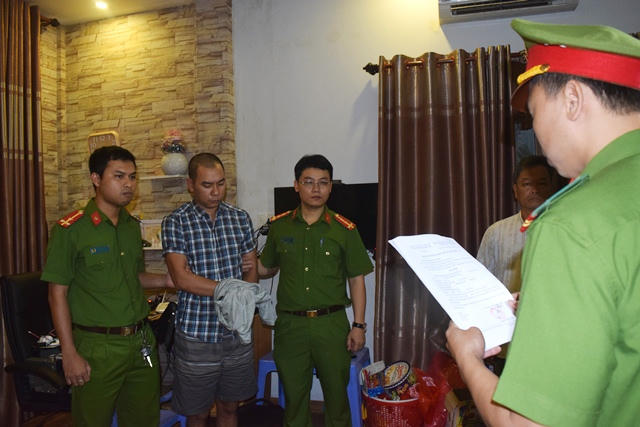 Công an đọc lệnh bắt một trong các đối tượng.