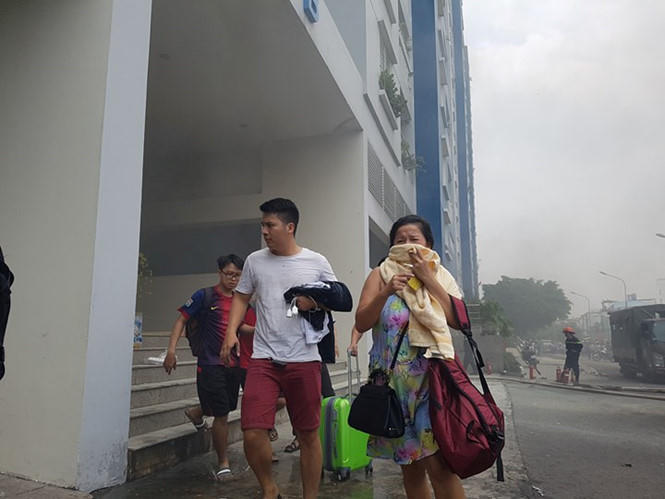 Người dân tháo chạy khi nghe lửa bùng phát trở lại ở chung cư Carina Plaza trưa nay  ẢNH: NGỌC DƯƠNG