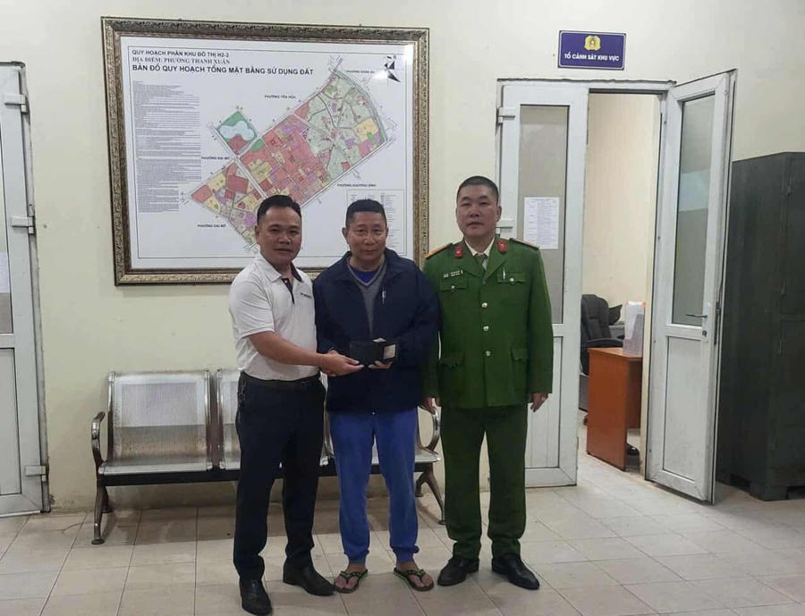 Đại diện Công an phường Thanh Xuân và Phóng viên Lã Thế Vinh (áo trắng) trao trả lại chiếc ví cho người bị mất.