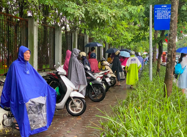 Bất chấp trời mưa các bậc phụ huynh ở lại cổng trường đội mưa chờ thông tin từ các sĩ tử.