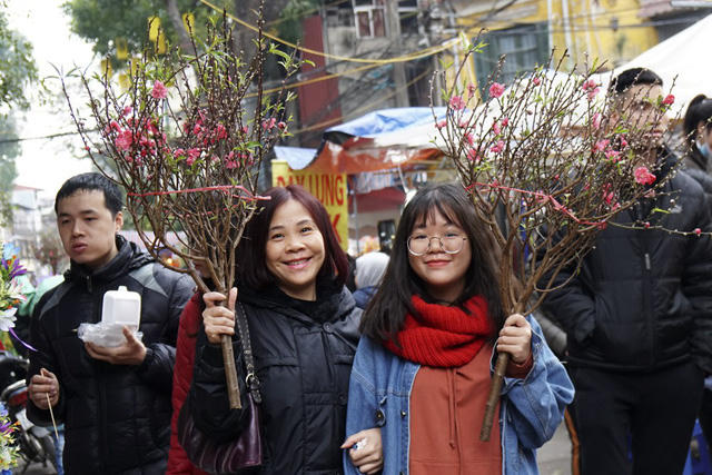Vẻ phấn khởi của những vị khách mua được cành đào vừa ý trong chợ hoa Hàng Lược.