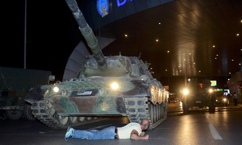 Metin Dogan nằm trước xe tăng tại sân bay Ataturk ở Istanbul đêm 15/7. (Ảnh: Reuters)