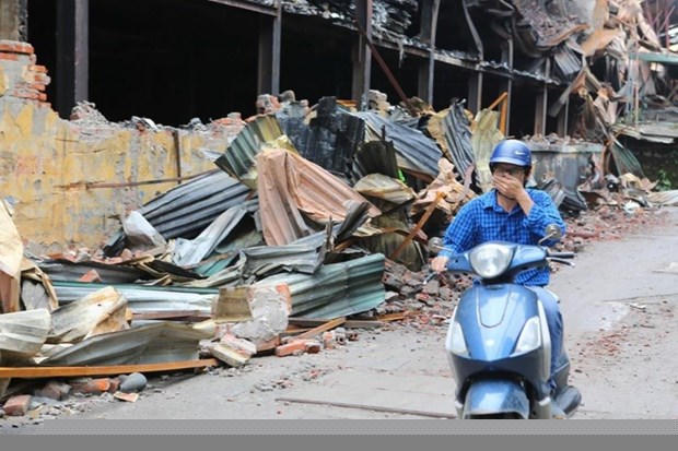Người dân sinh sống tại đây phải đeo khẩu trang mỗi khi đi qua khu vực cháy nhà máy Bóng đèn Phích nước Rạng Đông. (Ảnh: Thành Đạt/TTXVN).